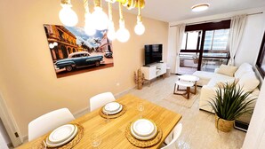 Una sala de estar moderna con comedor, televisor y balcón con vistas.