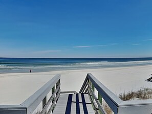 A wooden boardwalk leading to a beach with a clear blue sky. - Morning Glory (St. Augustine)