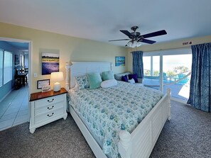 A bedroom with a bed, a nightstand, a ceiling fan, and a view of the outdoors. - Morning Glory (St. Augustine)