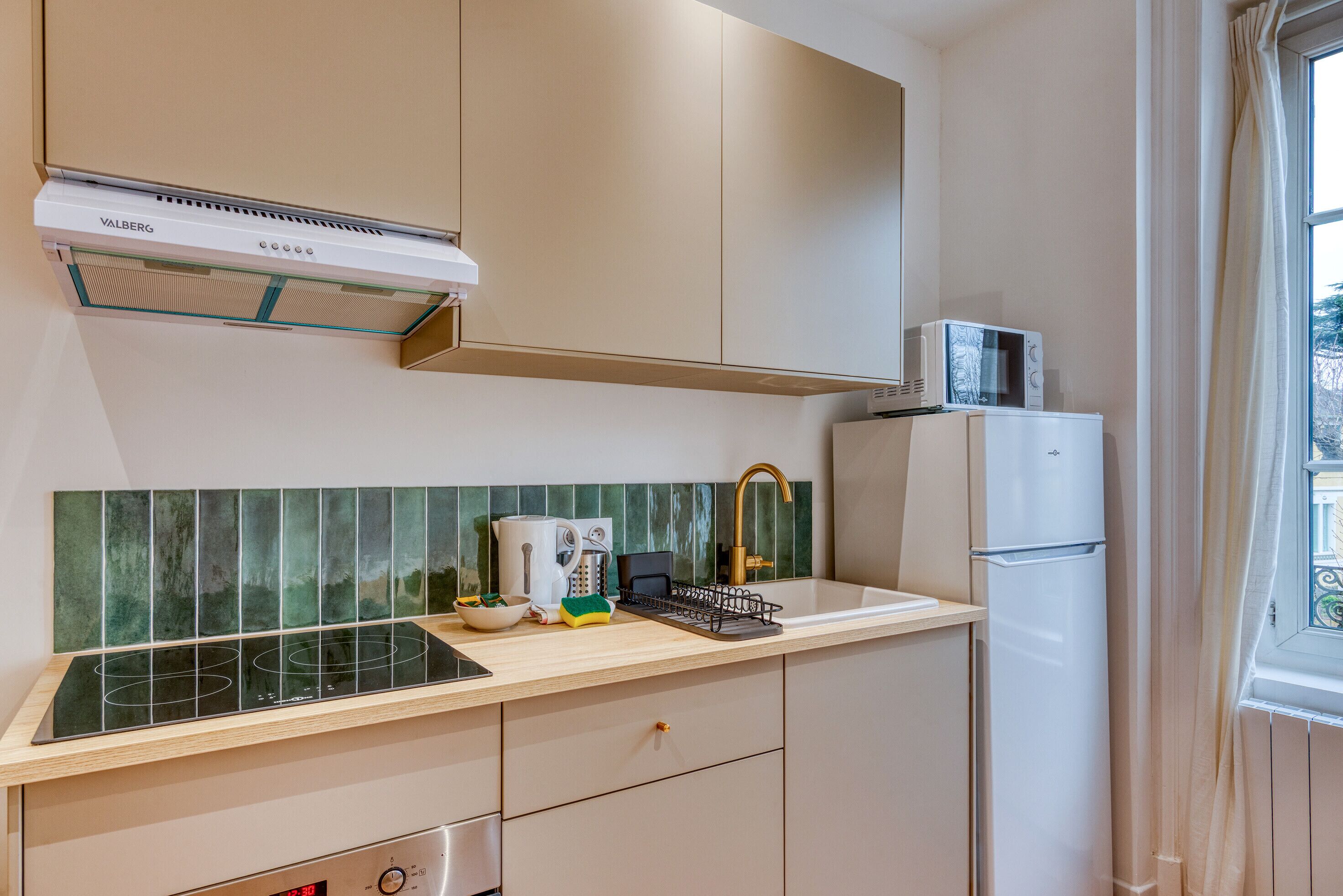 A compact kitchen with a built-in stove, a microwave, and a refrigerator.