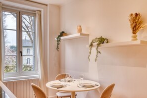 Un comedor con una mesa redonda, sillas y una ventana con cortinas.