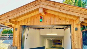 A wooden building with a green exit sign, a stone wall, and a paved entrance. - Bergliebe am Tegernsee: central, for 2, upscale, south-facing terrace, sauna, underground parking, near the lake (Rottach-Egern)