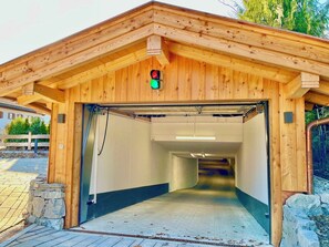 A wooden building with a green exit sign, a stone wall, and a paved entrance. - Bergliebe am Tegernsee: central, for 2, upscale, south-facing terrace, sauna, underground parking, near the lake (Rottach-Egern)