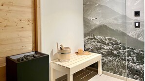 A room with a wooden wall, a bench with a bucket and a tray, and a mural of a mountainous landscape. - Bergliebe am Tegernsee: central, for 2, upscale, south-facing terrace, sauna, underground parking, near the lake (Rottach-Egern)