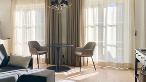 A modern living room with a sofa, two chairs, a round table, and a chandelier. - Bergliebe am Tegernsee: central, for 2, upscale, south-facing terrace, sauna, underground parking, near the lake (Rottach-Egern)