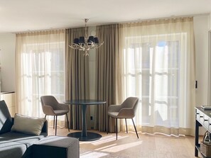 A modern living room with a sofa, two chairs, a round table, and a chandelier. - Bergliebe am Tegernsee: central, for 2, upscale, south-facing terrace, sauna, underground parking, near the lake (Rottach-Egern)