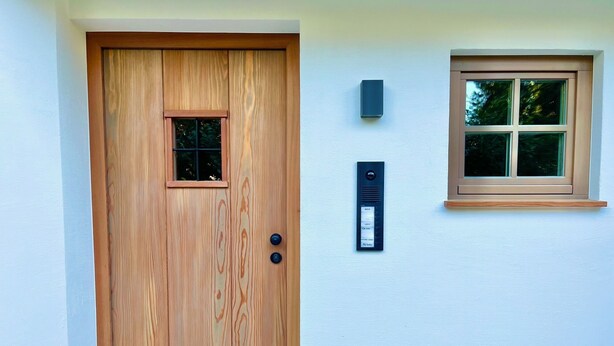 A wooden door with a small window, a wall-mounted intercom, and a window with a wooden frame. - Bergliebe am Tegernsee: central, for 2, upscale, south-facing terrace, sauna, underground parking, near the lake (Rottach-Egern)