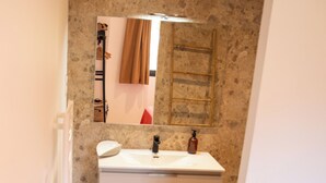 A bathroom with a stone wall, a white sink, a mirror, and a towel rack. - VILLA NEPITA Modern 1-bedroom with private pool (Porto-Vecchio)
