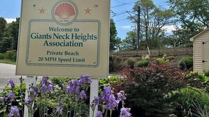 Señal de bienvenida de la Asociación Giants Neck Heights con límite de velocidad de 20 millas por hora.