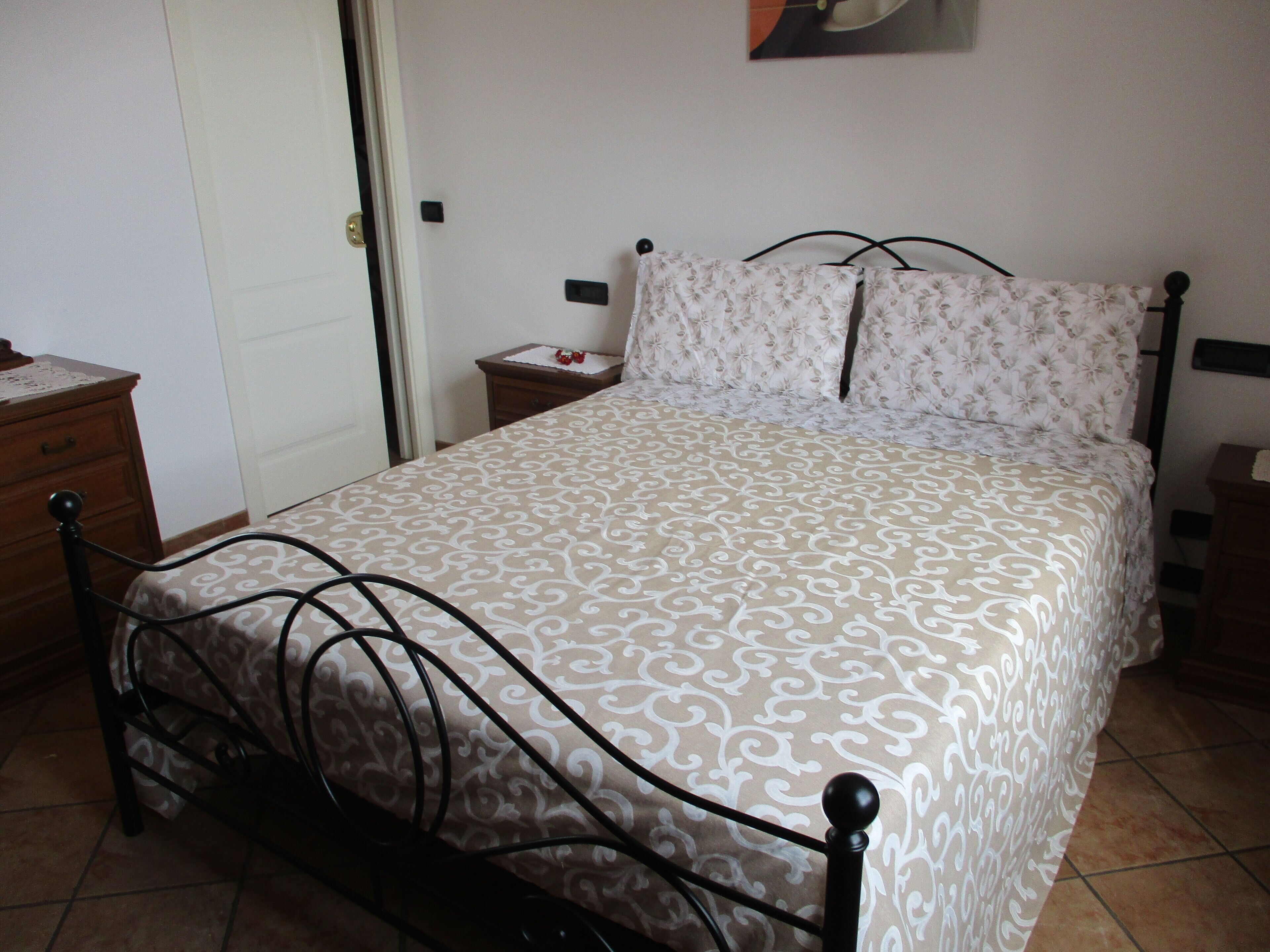 Un dormitorio con cama, mesita de noche, cómoda y puerta.