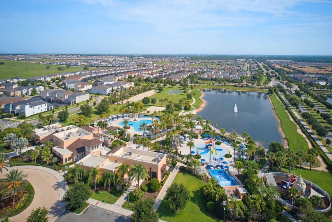 Een luchtbeeld van een resort met meerdere zwembaden, een groot meer en een verzorgd landschap.
