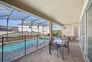 Ein überdachter Außenbereich mit Pool, Terrassenmöbeln und Blick auf die Umgebung.