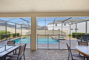A covered outdoor area with a pool, seating, and a view of neighboring buildings. - 9BR The Sunset Paradise Resort w/ Pool Near Disney (Kissimmee)