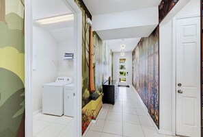 Ein Flur mit einer Waschmaschine, einer Sitzbank und einem Mülleimer.