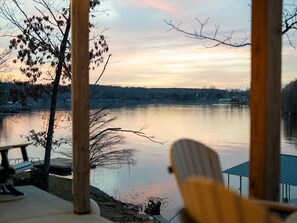 A lakeside view from a wooden deck with a chair, overlooking a calm lake and distant shoreline. - Hot tub, Waterfront, Sunset Views, Dock, Lilypad, The Blue Blessing (Goreville)