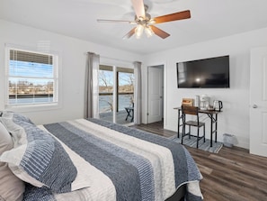 A bedroom with a bed, a ceiling fan, a TV, and a view of the outdoors. - Blue Blessing, Hot tub, Waterfront, bunk room (Goreville)