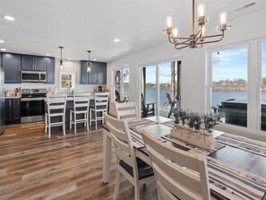 A modern kitchen with dark cabinets, a stainless steel microwave, and a dining area with a wooden table and chairs. - Hot tub, Waterfront, Sunset Views, Dock, Lilypad, The Blue Blessing (Goreville)