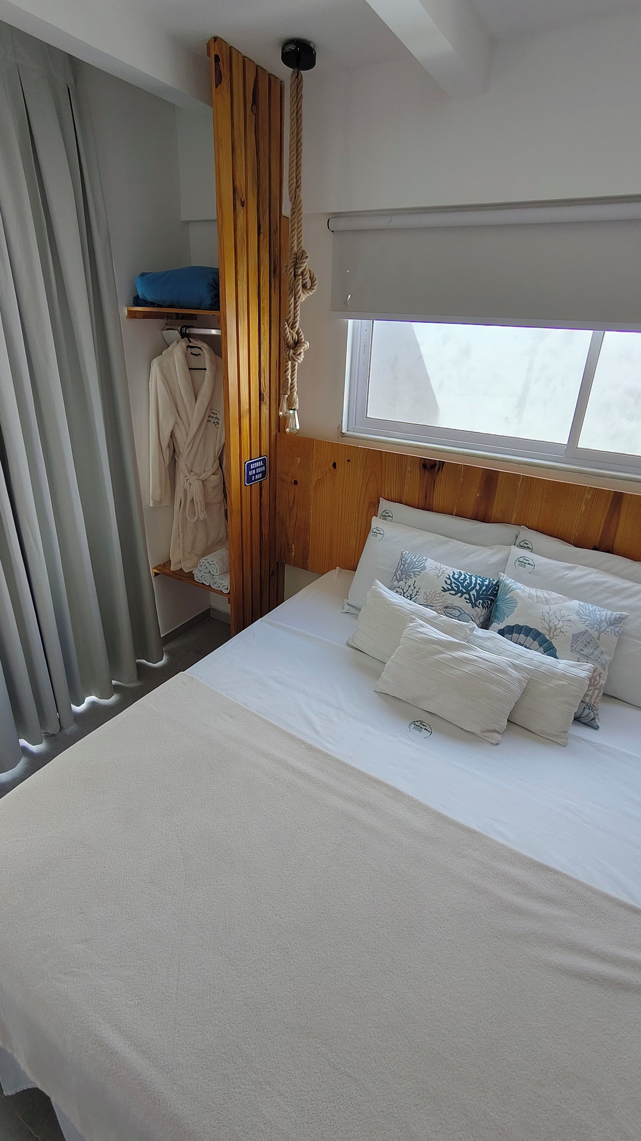 Ein Hotelzimmer mit Bett, einem Holzschrank, einem Fenster mit Blick und einem Handtuchhalter.