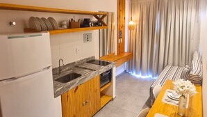 A compact kitchen with a refrigerator, double sink, wooden cabinets, and a wooden countertop.