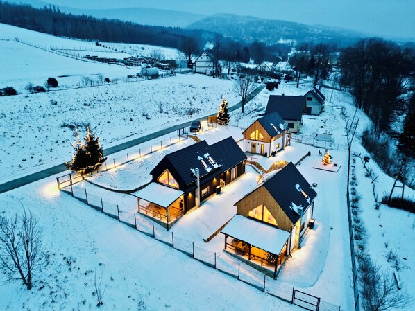 A snow-covered landscape with a cluster of wooden houses connected by a fence. - Izera Polana Also bookable as 2-3 houses (Świeradów-Zdrój)