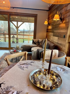 A cozy room with a large window, a wooden wall, and a table set with candles and pinecones. - Izera Polana Also bookable as 2-3 houses (Świeradów-Zdrój)