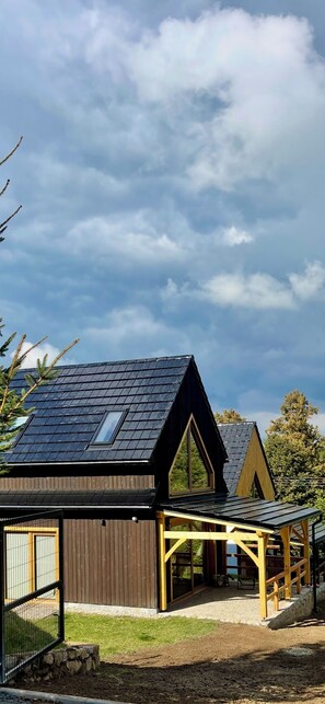 A modern house with a sloped roof, a fenced yard, and a covered outdoor seating area. - Izera Polana Also bookable as 2-3 houses (Świeradów-Zdrój)