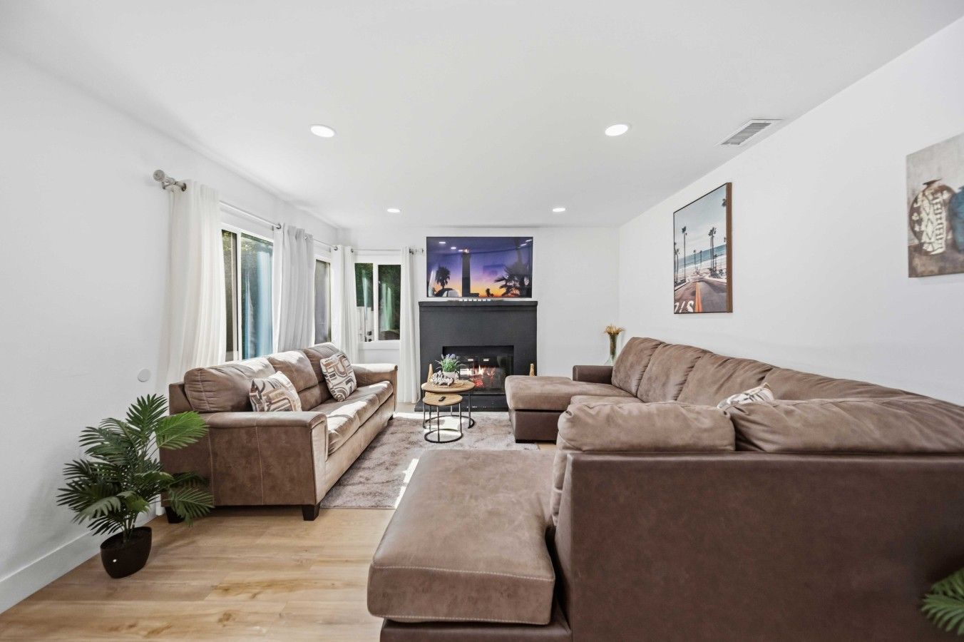 A modern living room with a fireplace, two sofas, a coffee table, and a potted plant.
