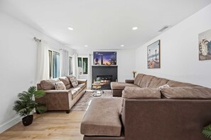 Een moderne woonkamer met een open haard, twee banken, een salontafel en een potplant.