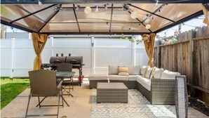 Un patio techado con una parrilla, asientos y un tapete estampado.