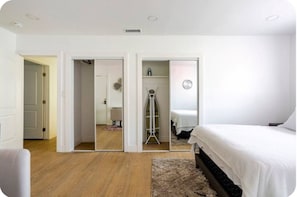 Une chambre à coucher avec un lit, un dressing et un couloir menant à une autre pièce.