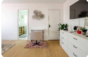 Une chambre moderne avec un bureau blanc, une chaise, un grand miroir et une commode blanche.