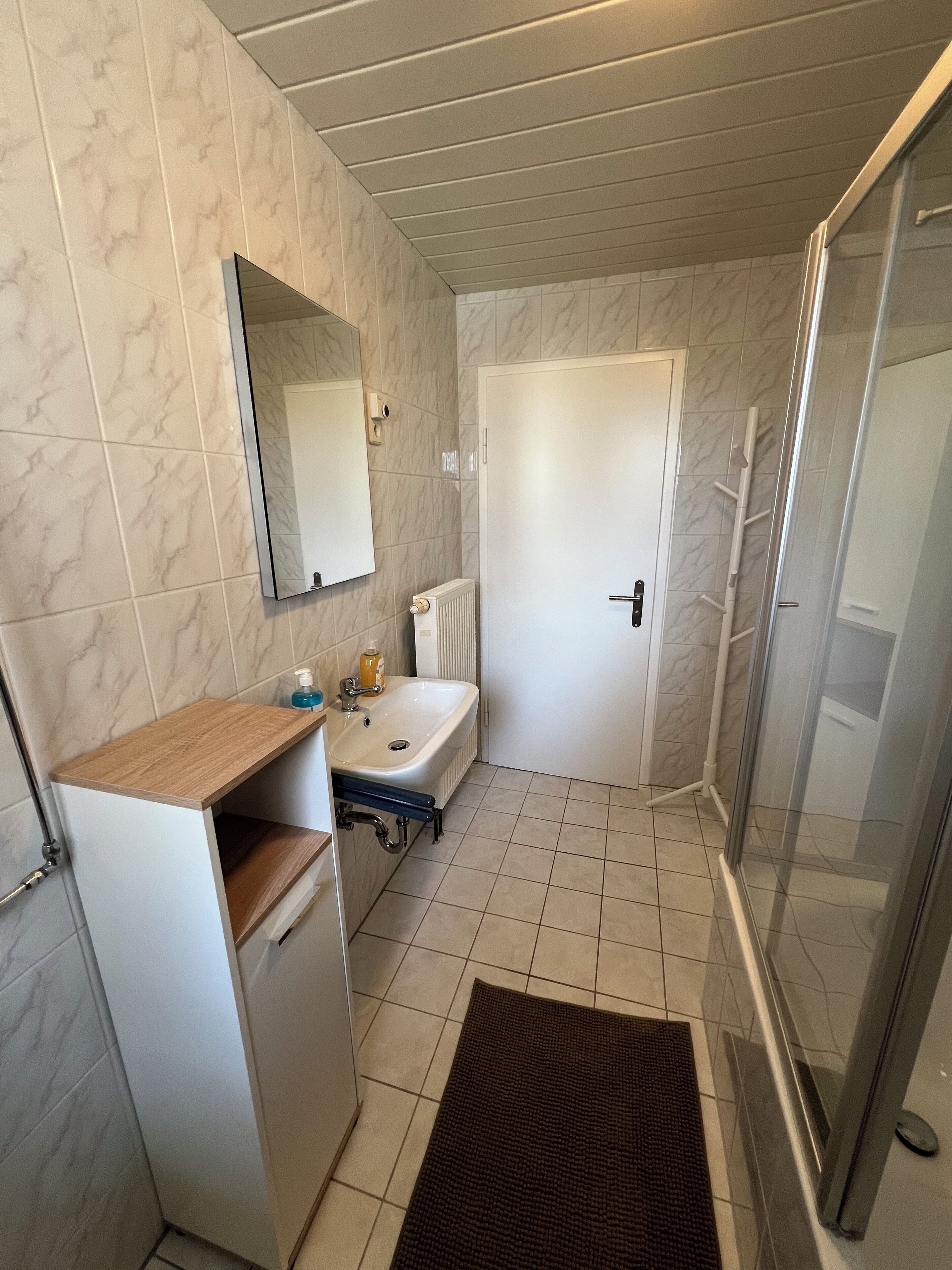 Een badkamer met een wit wastafel, spiegel en douche.