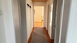 A hallway with a wooden ceiling, white walls, and a striped rug leading to a door. - Vacation apartment Oberland Ammersee Landsberg (Pürgen)