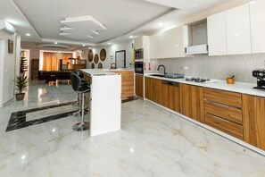 Una cocina moderna con piso de mármol, armarios de madera y una isla central con taburetes de bar.