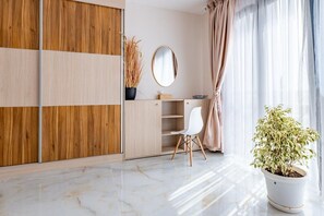 Una habitación moderna con un armario de madera, una silla blanca, un espejo redondo y una planta en maceta.