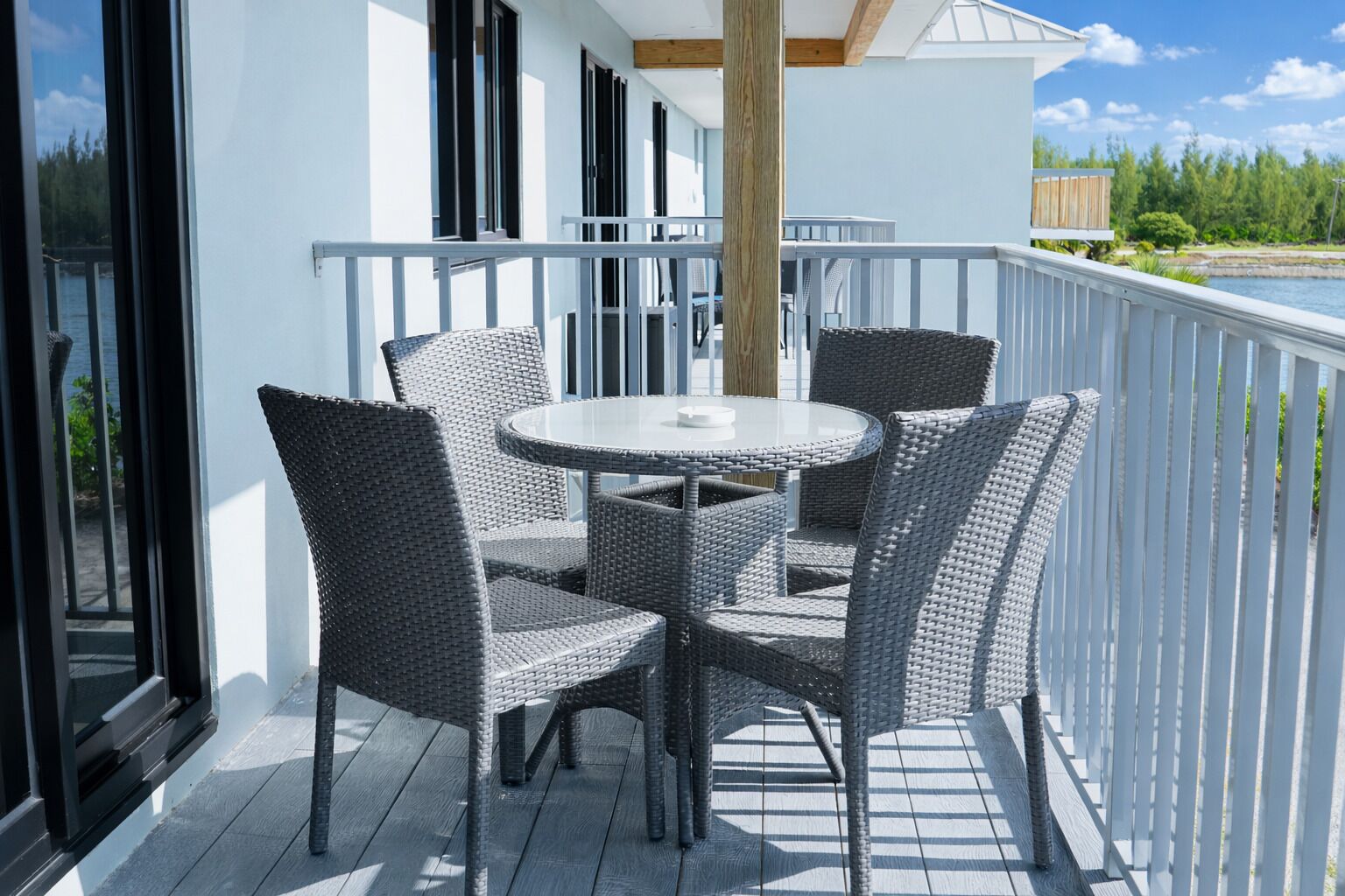 A balcony with wicker furniture, a round table, and a view of the water.