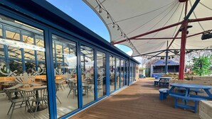 A covered outdoor seating area with wooden flooring and blue tables. - North Wales Coastal Stay (Rhyl)
