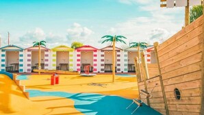 A children's play area with colorful buildings, a slide, and a wooden ship structure. - North Wales Coastal Stay (Rhyl)