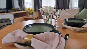 A dining table with plates, glasses, and a napkin. - North Wales Coastal Stay (Rhyl)