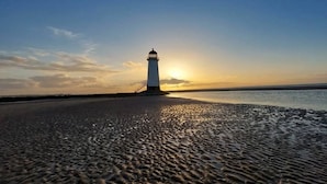 A lighthouse on a beach with a clear sky. - North Wales Coastal Stay (Rhyl)
