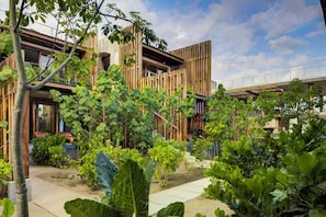 A modern building with a wooden facade, surrounded by lush greenery and a clear sky. - NANANA Hotel del Mar (Puerto Escondido)