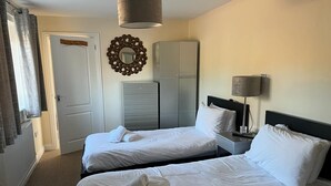 Camera d'albergo con due letti, un armadio, uno specchio, una lampada e una porta.