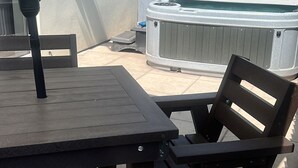 Una zona patio all'aperto con tavolo e sedie, una vasca idromassaggio e una zona relax coperta.