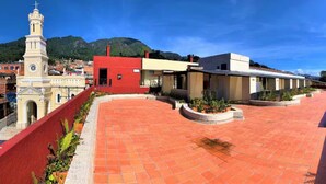 A courtyard with red-tiled flooring, a clock tower, and buildings with red and beige facades. - Lovely loft downtown - La Candelaria (Bogotá)