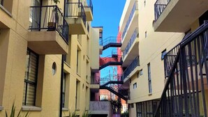 A narrow pedestrian pathway between multi-story buildings with balconies, surrounded by greenery and a clear sky. - Lovely loft downtown - La Candelaria (Bogotá)