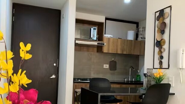 A modern kitchen with wooden cabinets, a black countertop, and a black chair. - Lovely loft downtown - La Candelaria (Bogotá)