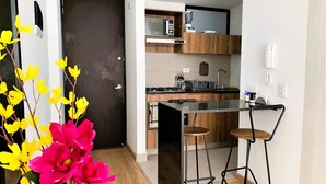 Une cuisine compacte dotée d’un îlot central, de meubles en bois et d’un plan de travail noir.