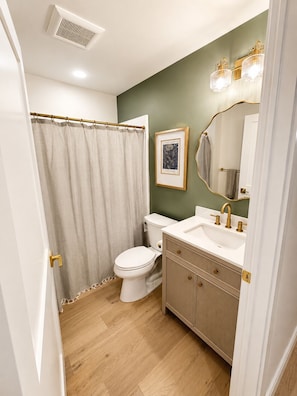 Un baño con inodoro, lavamanos y cortina de ducha.