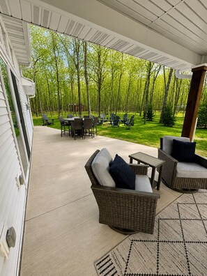 Un área de patio al aire libre con muebles de mimbre, una mesa y sillas.