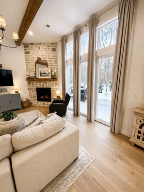 Ein gemütliches Wohnzimmer mit Kamin, einer Couch, einem Fernseher und einer Steinwand.
